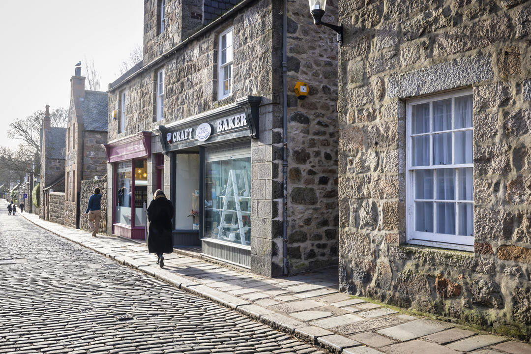 People walking along a traditional cobbled British high street.