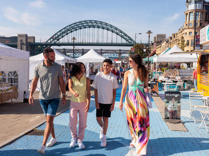 Family walking through stalls at a market in a city