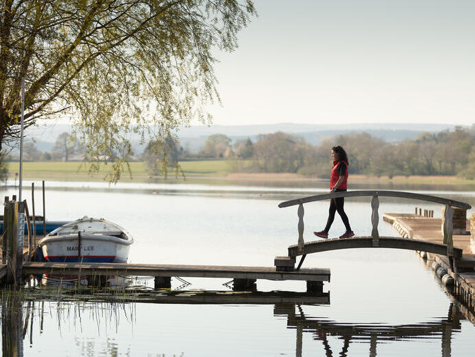 Una donna attraversa un ponte, vicino a una barca ormeggiata.