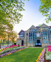 Historic house surrounded by trees and a garden in bloom