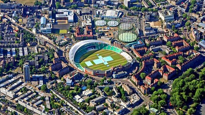 Aerial view scanning over city with large cricket ground, parks and buildings