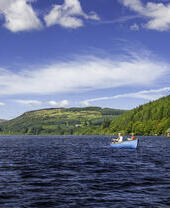 A father and son on a boat, fishing on a lake.
