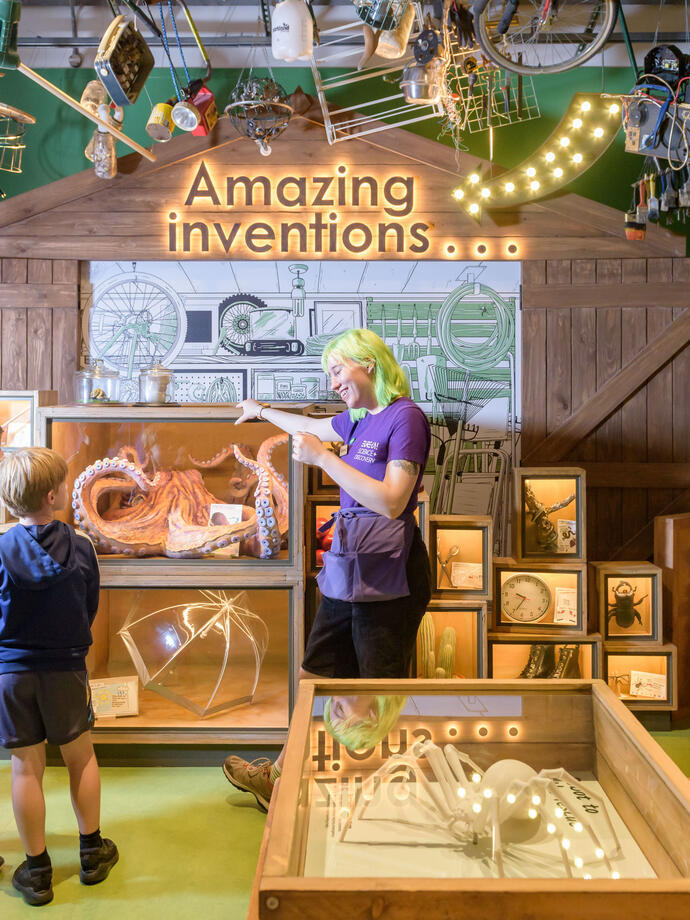 A woman showing children an exhibit at a Science + Discovery Centre.