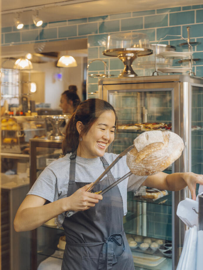 Smiling woman lifting loaf of bread with tongs