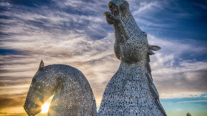 Pair of enormous horse head sculptures at sunset.