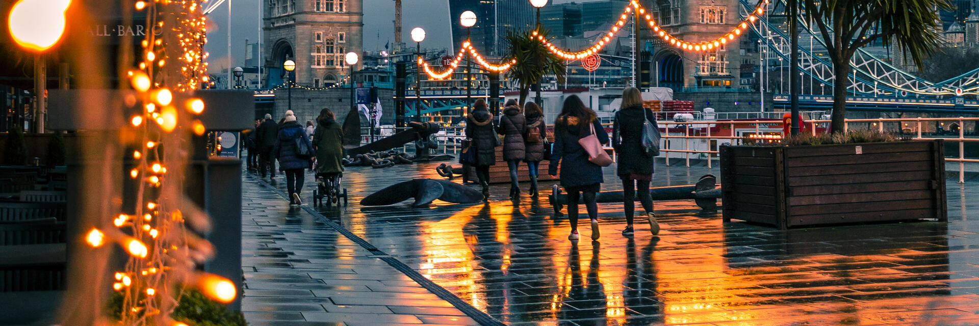 Menschen, die nachts an Lichterketten auf einer Stadtstraße vorbeigehen