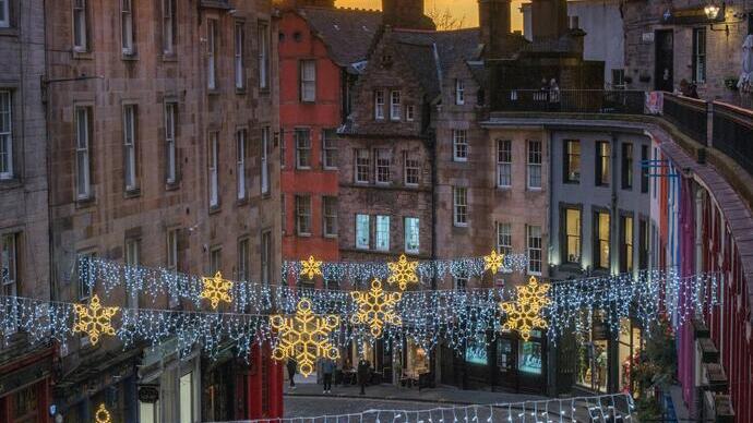 View looking down onto a pretty street with Christmas decorations lit up at dawn with sunrise in background.