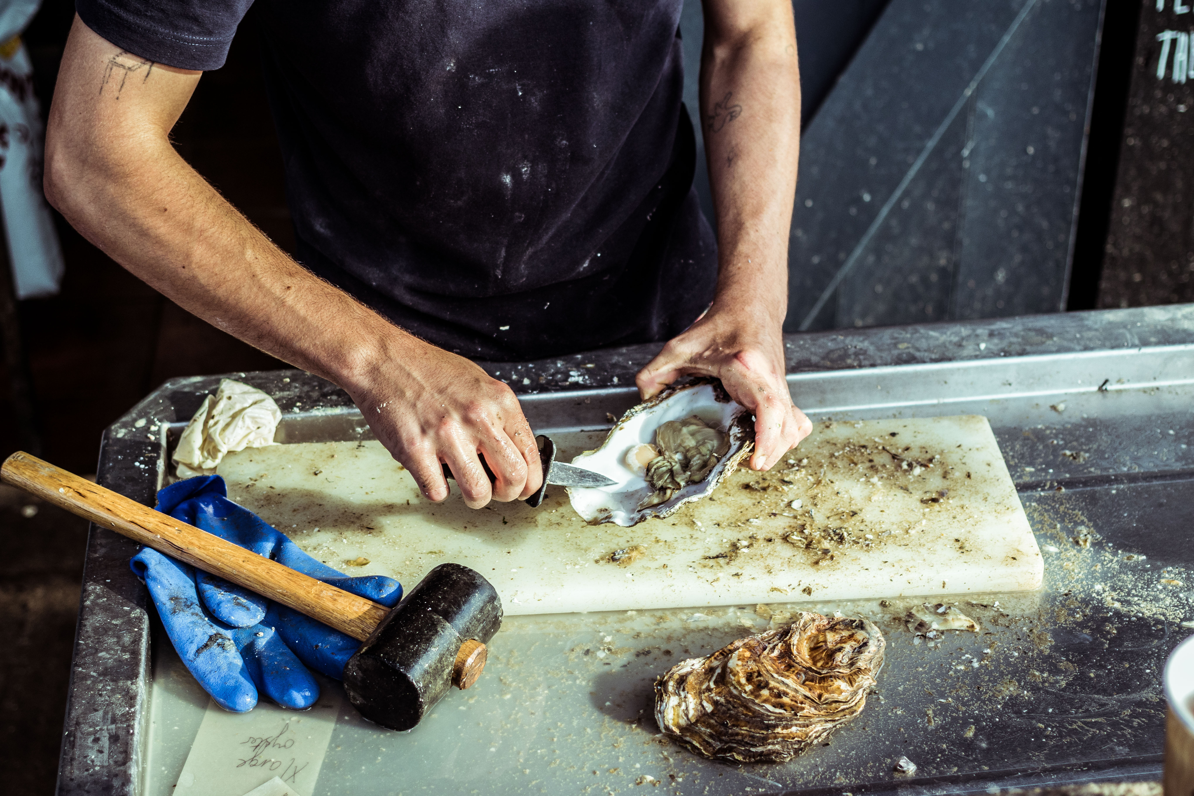 A man prepares an oyster at a seafood market in Whitstable, England