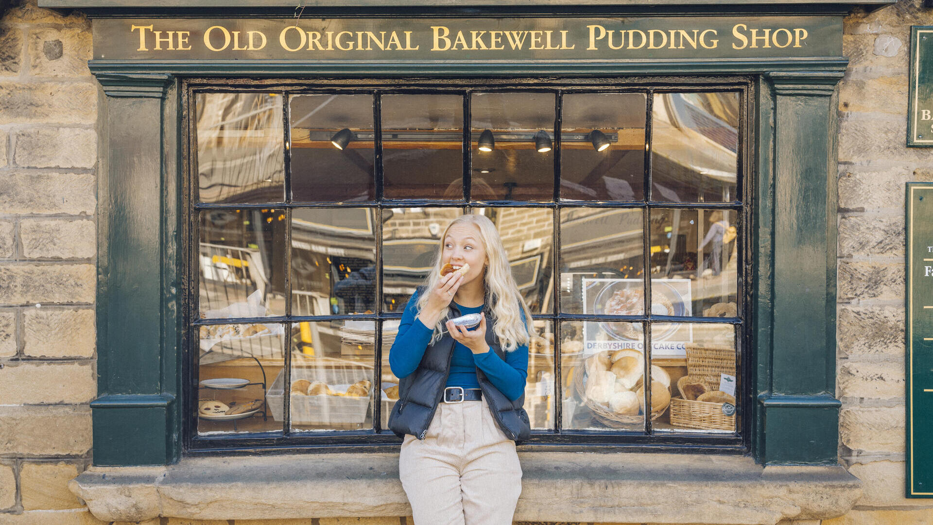 Donna che mangia una torta Bakewell davanti a una panetteria