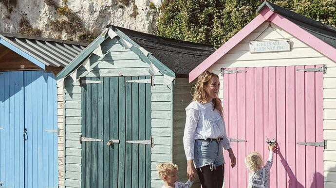 Woman and two children in front of a row of beach huts