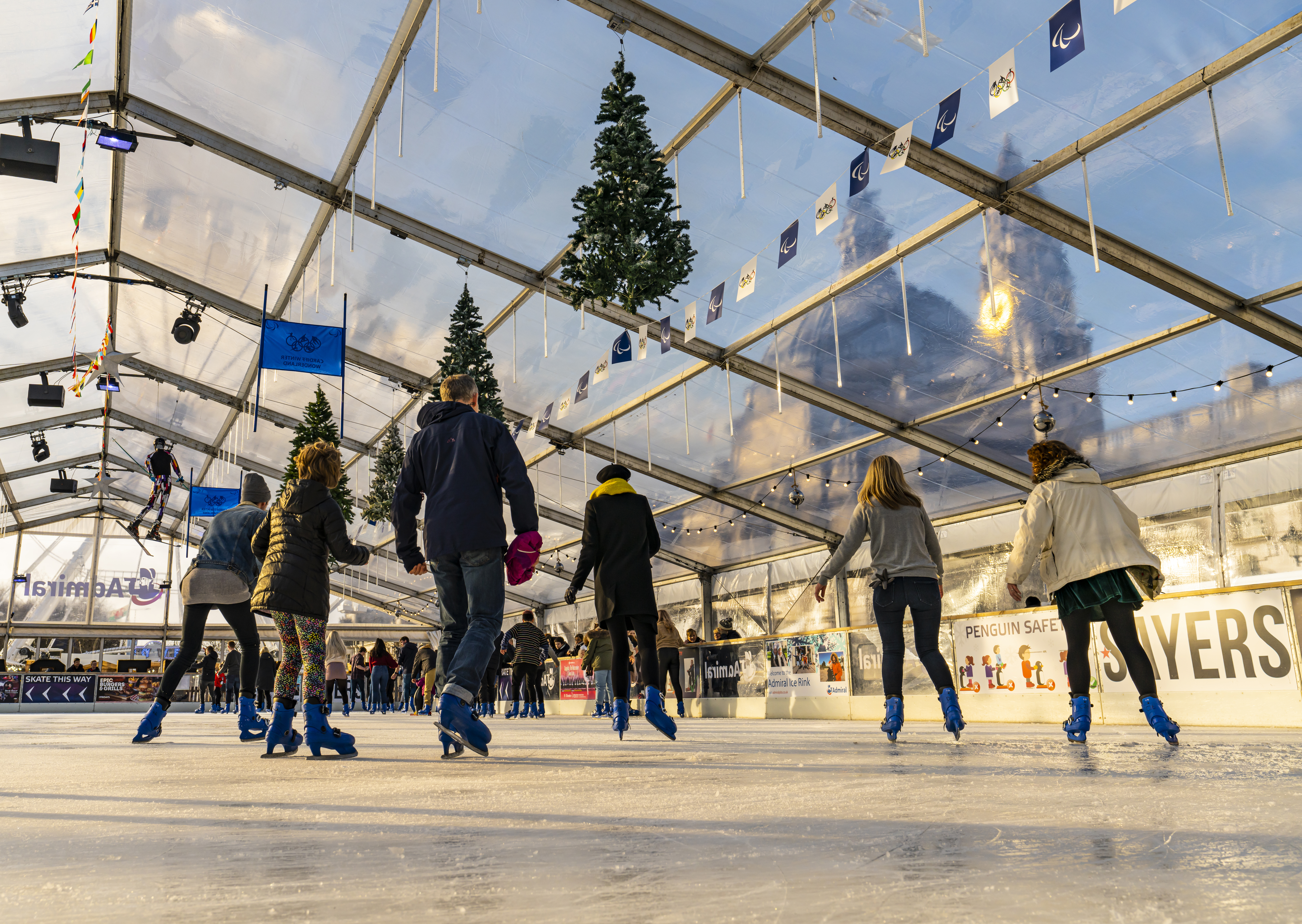 Menschen, die auf einer Eislaufbahn unter einem Glasdach Schlittschuh laufen