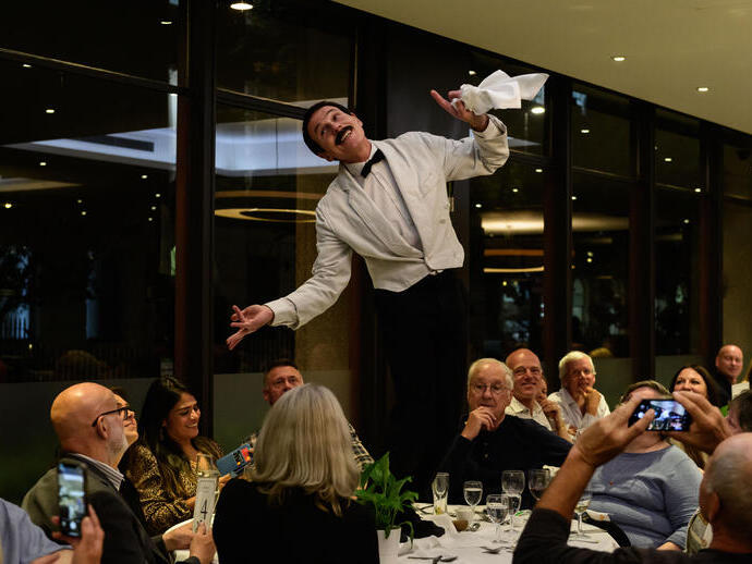Acteurs en costume sur le plateau d'une pièce burlesque avec un serveur paradant sur une table.