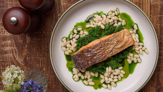 A fish dish at on a kale leaf and beans