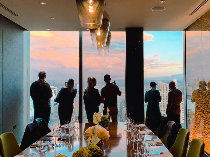 A group of people drinking while looking out over Manchester's skyline in a private room at 20 Stories Restaurant
