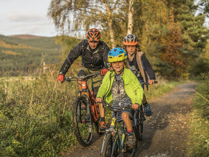Adult and two children cycling on a path through the countryside