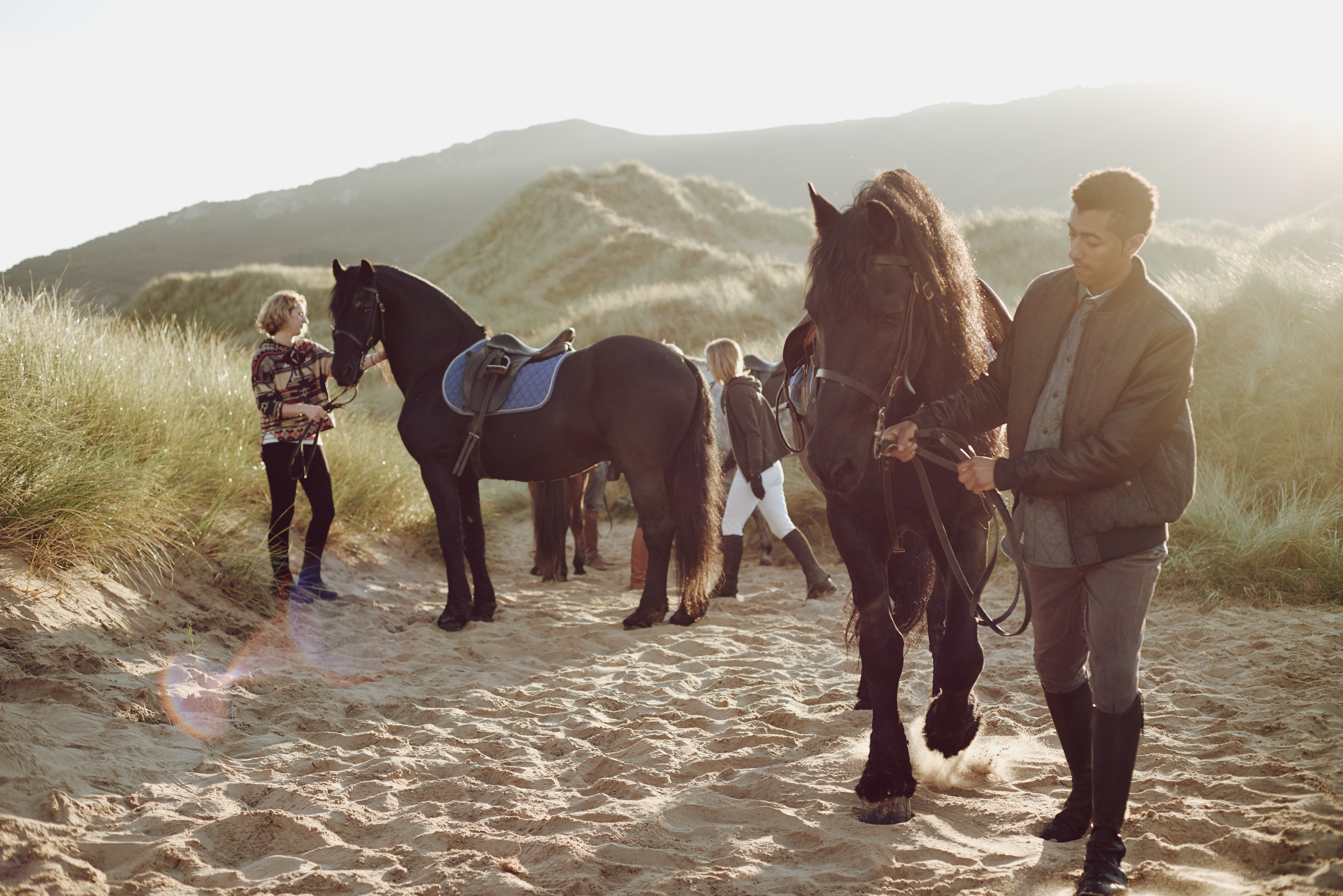 People leading horses along beach by their harness