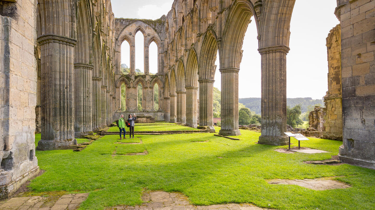 Deux amies dans la nef centrale d'une abbaye en ruines sous le soleil