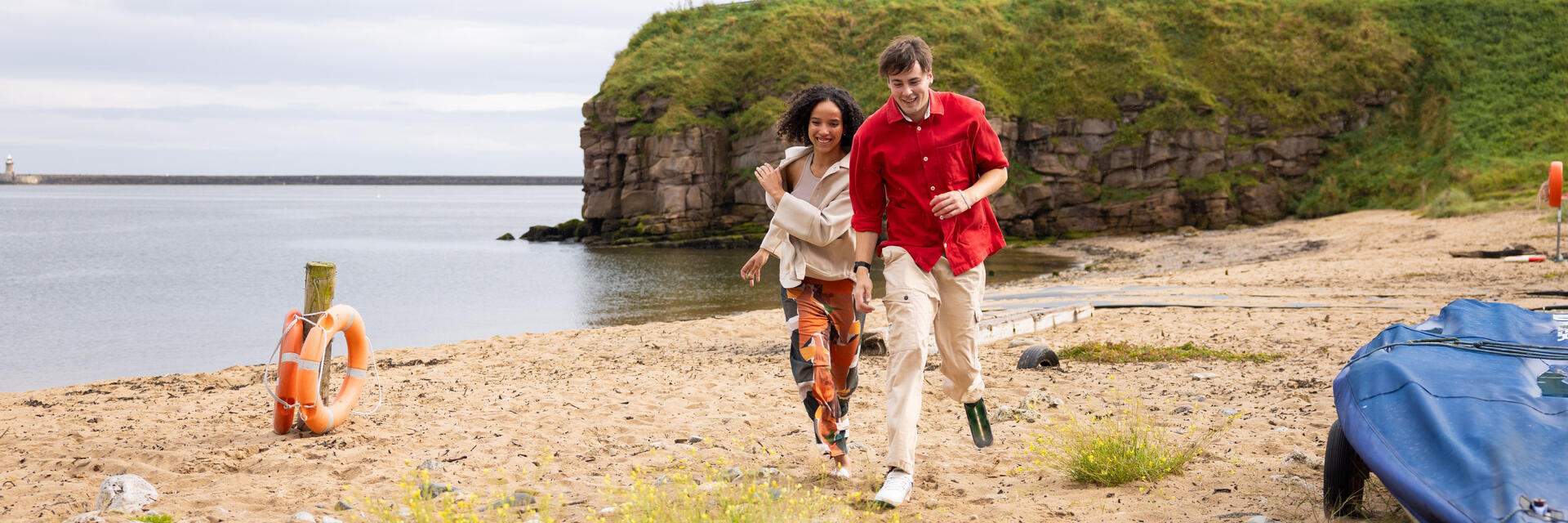 Couple running on the beach, the man has a prosthetic leg