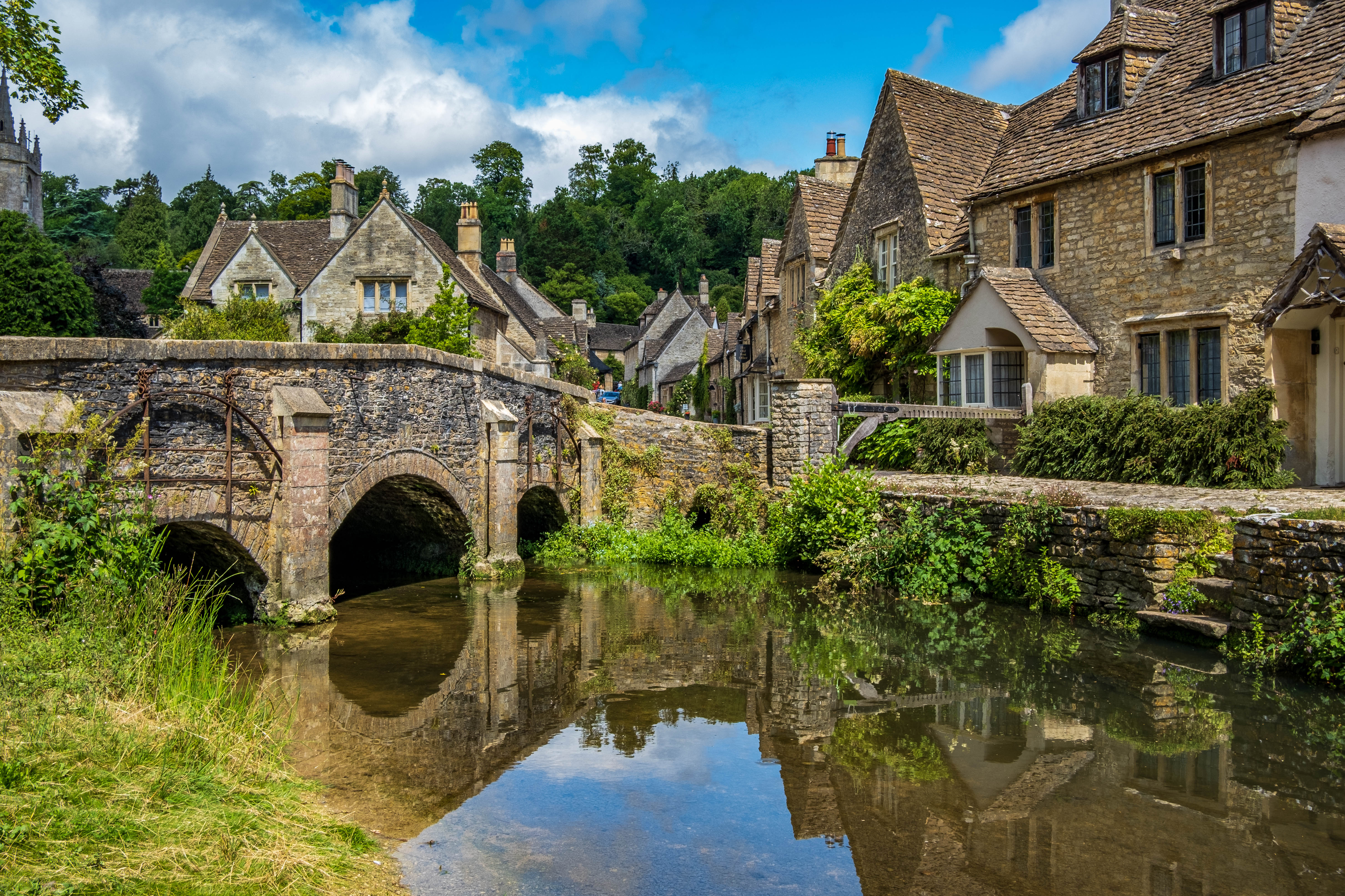 Blauer Himmel und Spiegelungen im malerischen Cotswold-Dorf Castle Combe.