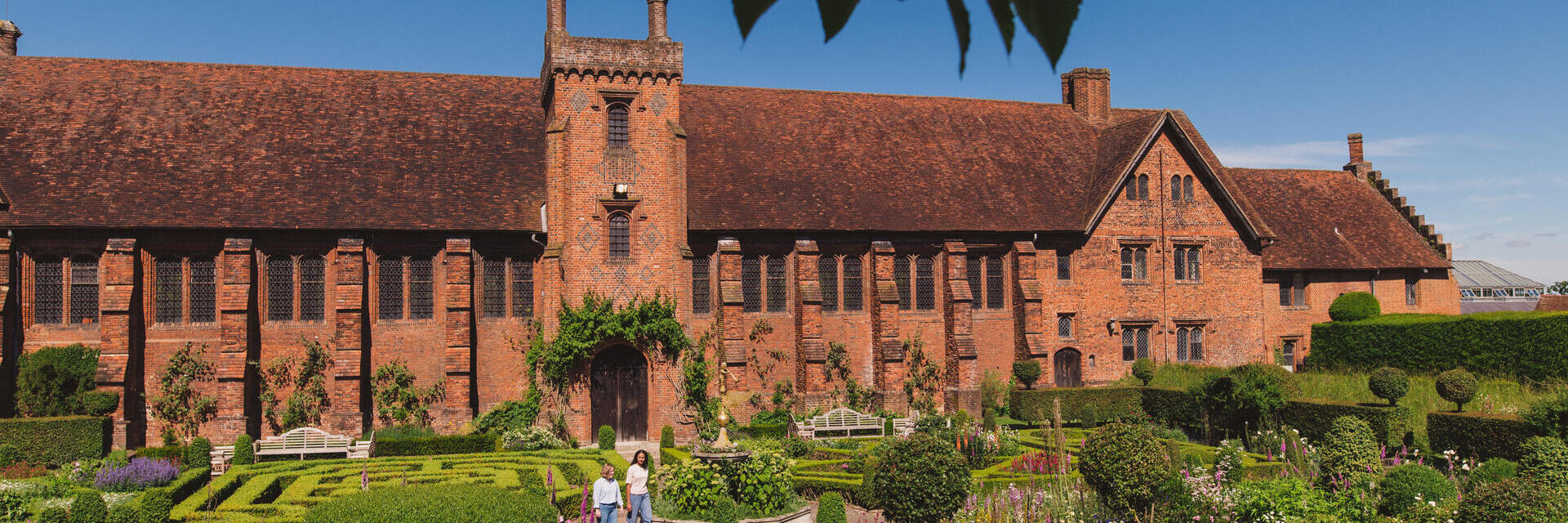Two women walk through the gardens of a heritage house