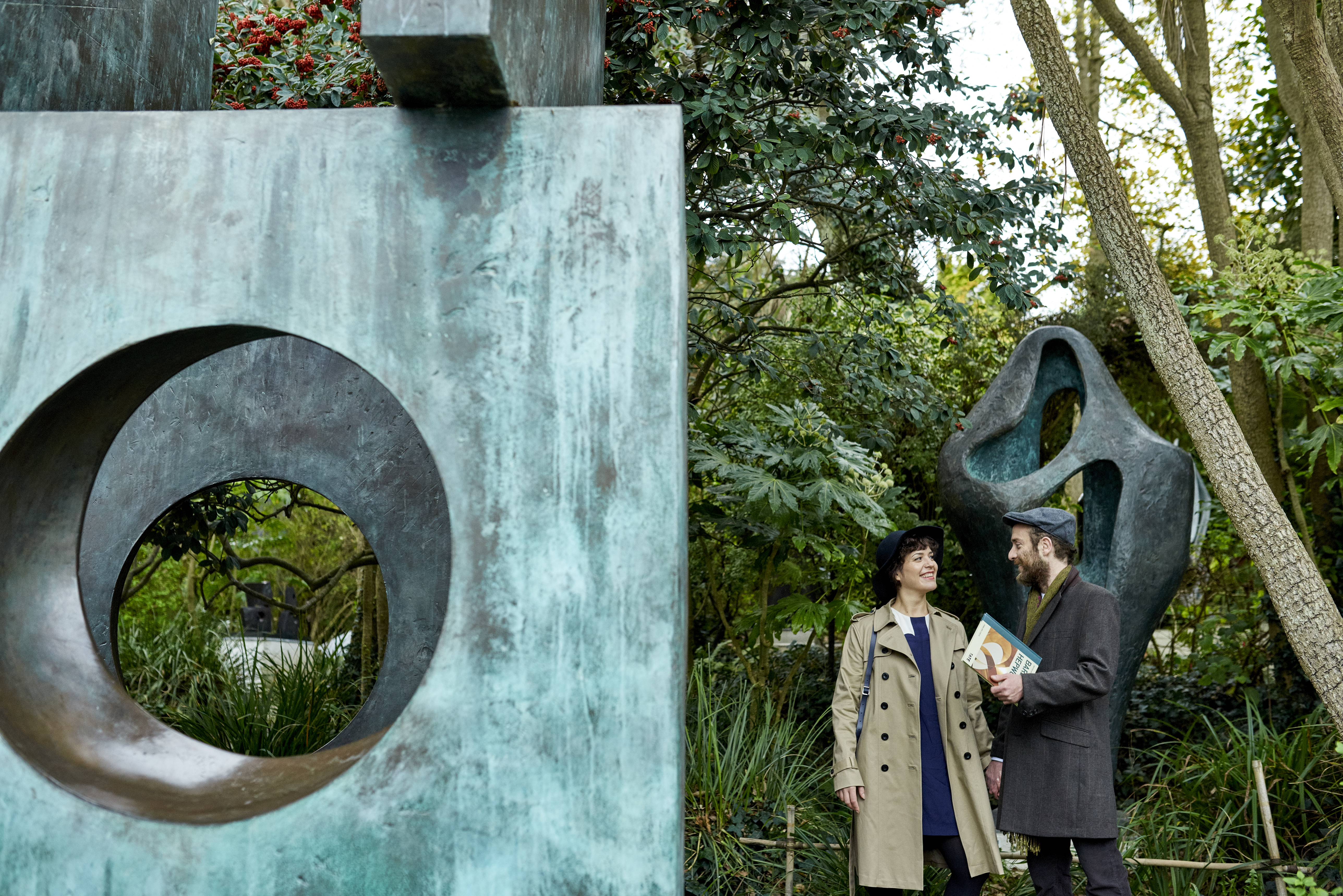 Couple standing next to bronze sculptures in a garden