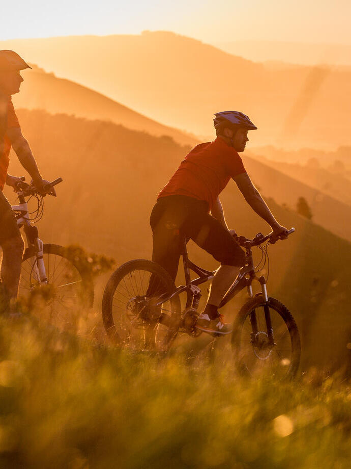 Two men on mountain bikes cycling at Devil's Dyke. Sunrise
