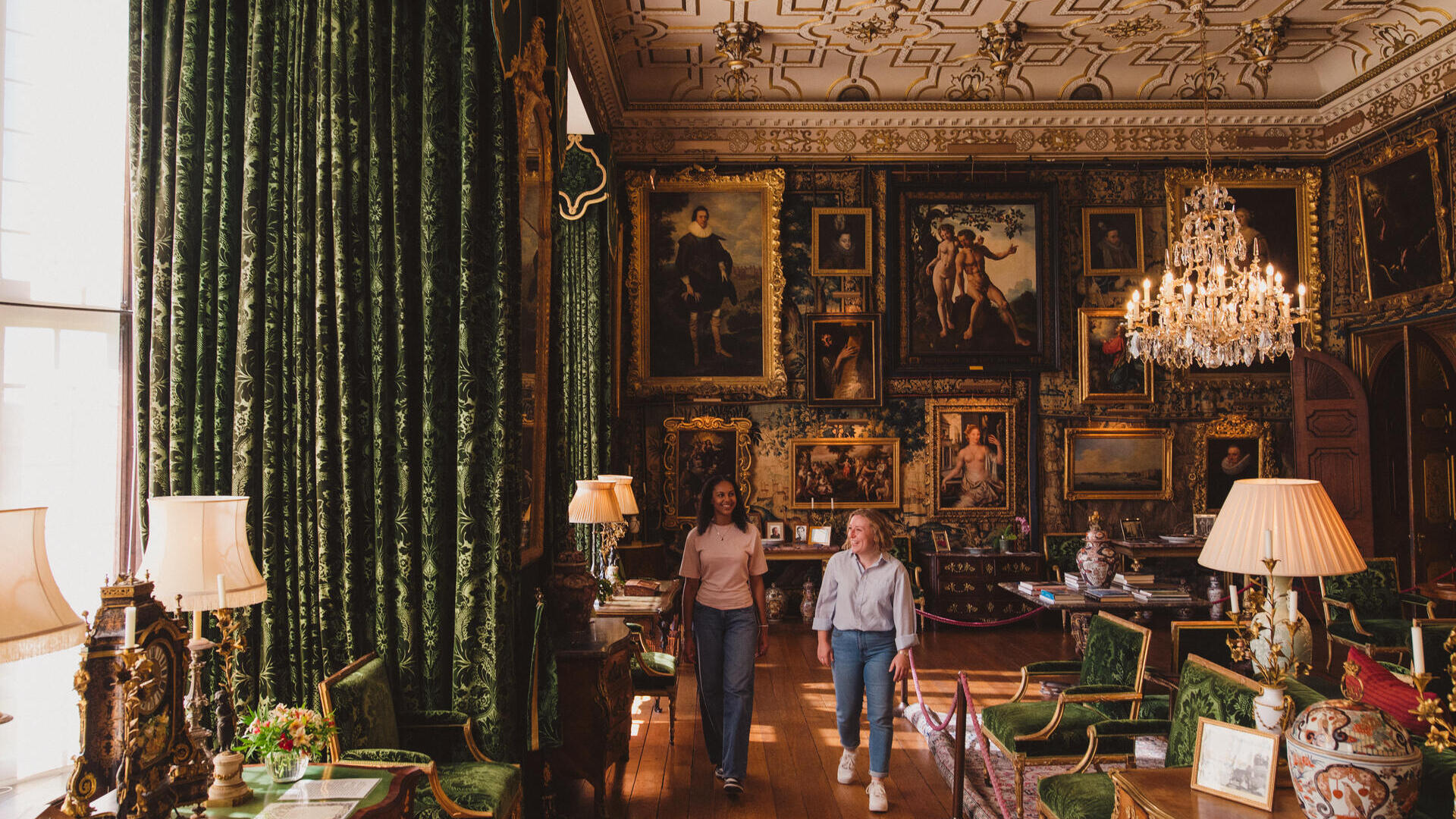 Two women walk through an ornate room in a heritage house