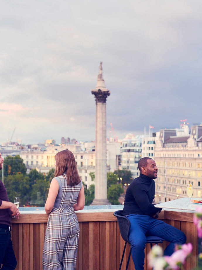 People having a drink at a rooftop bar in a city
