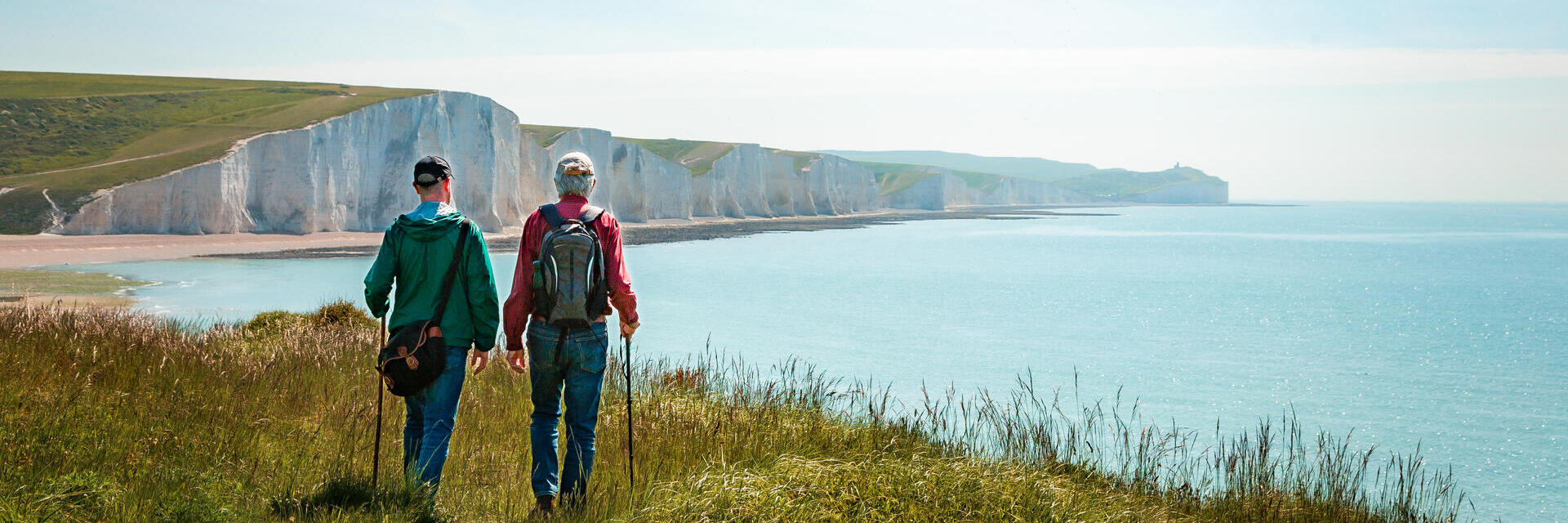 Two men hiking together with the stunning backdrop of white cliffs overlooking the ocean.