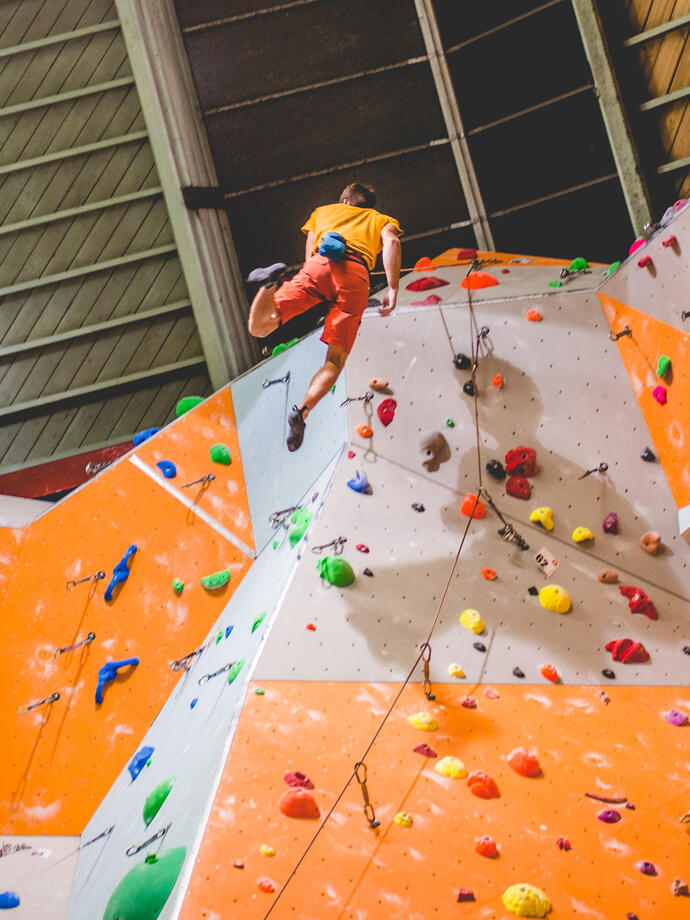 A man climbing up an indoor climbing wall 