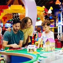 Mother, father and son laughing whilst playing with Lego