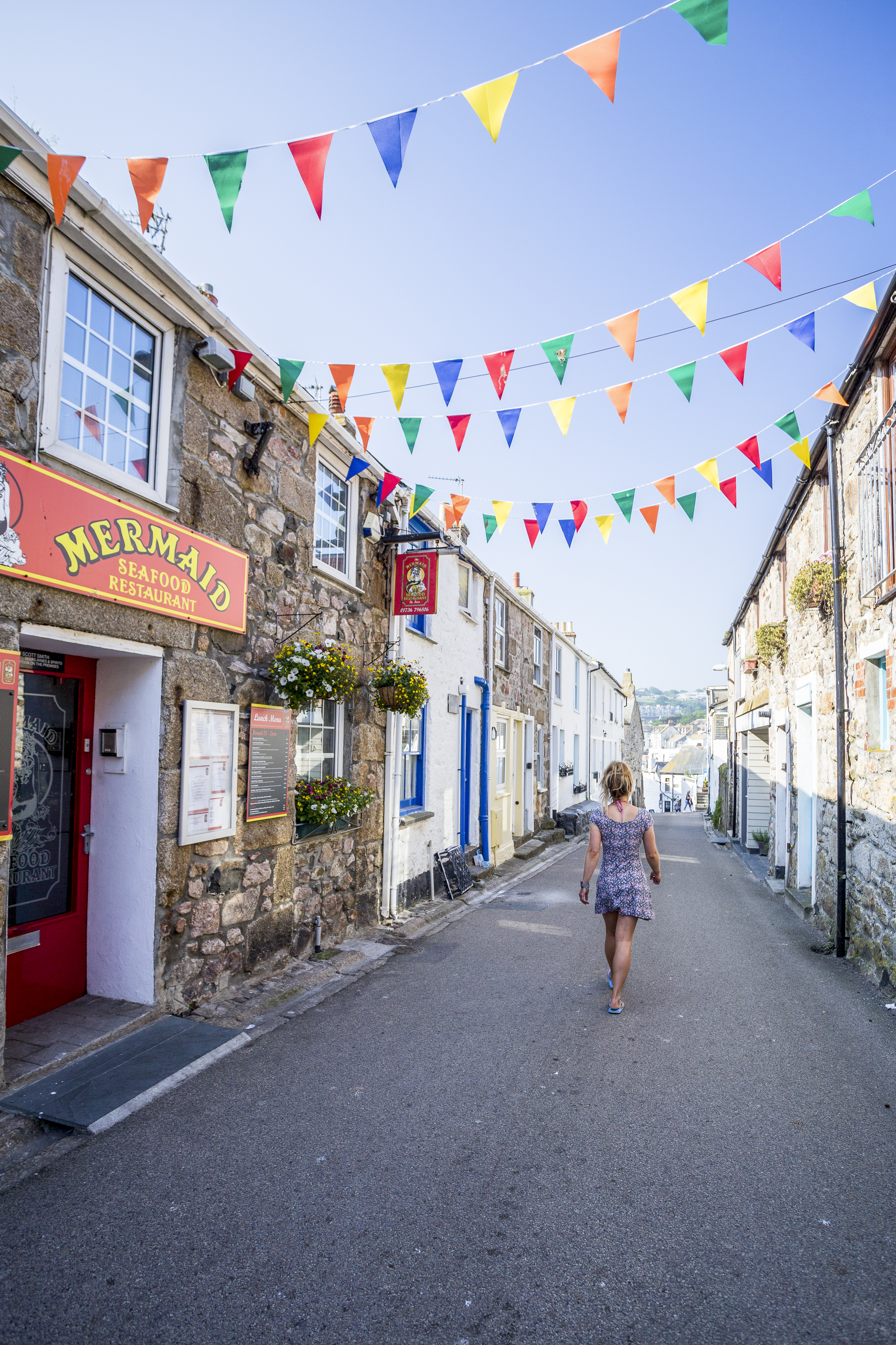Woman walking down a street below rainbow bunting
