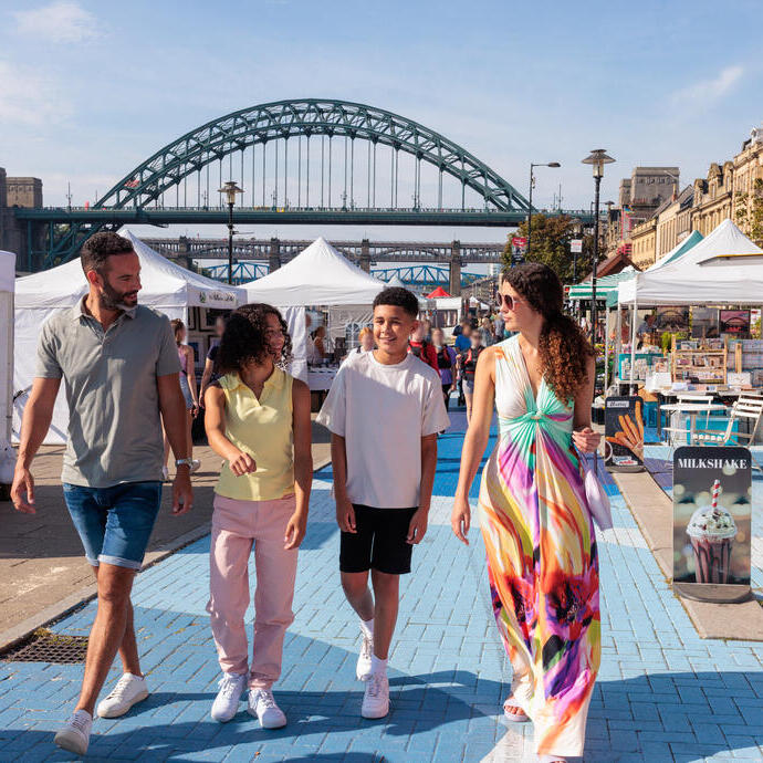 Family walking through stalls at a market in a city