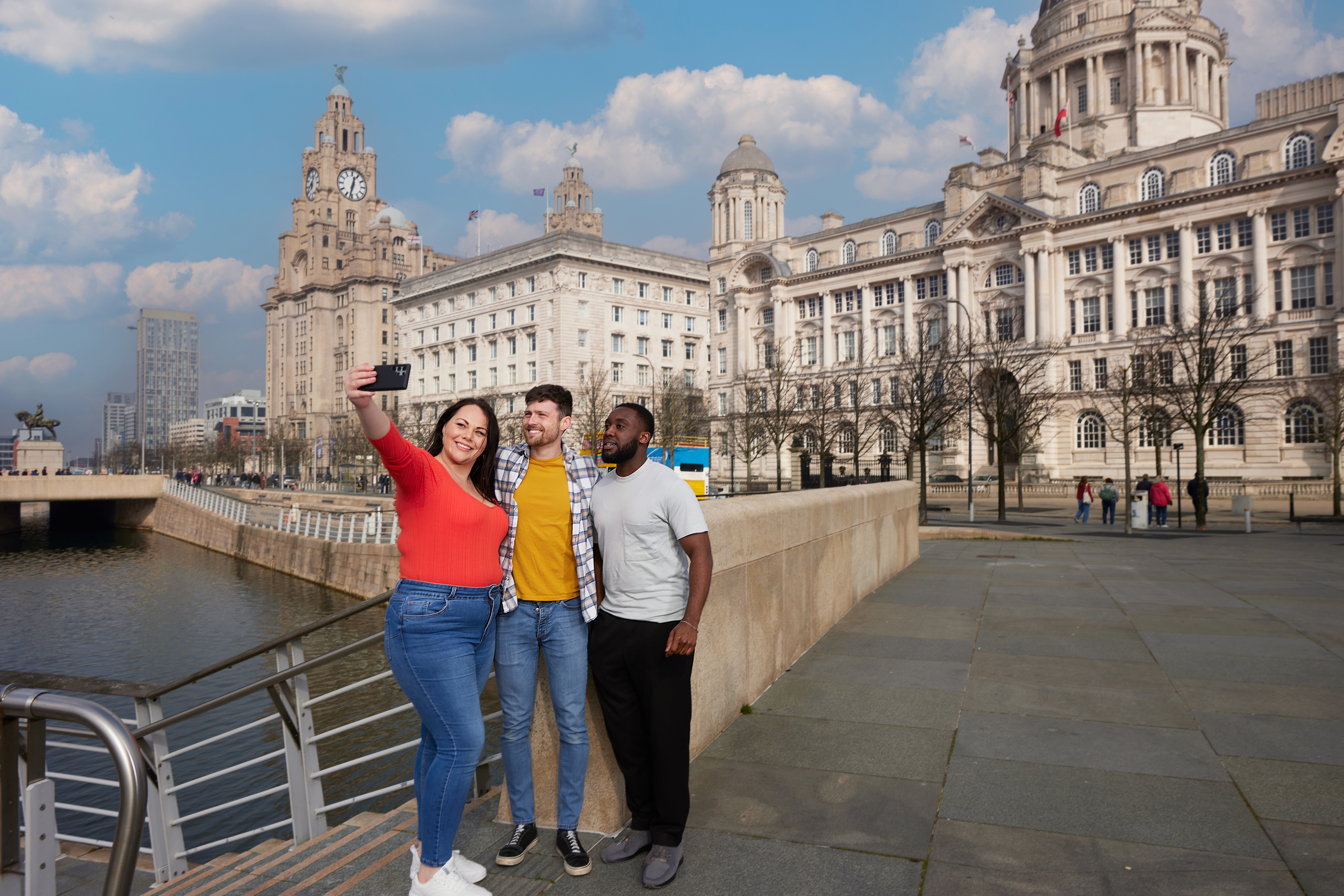 Friends taking a selfie by a city waterfront.