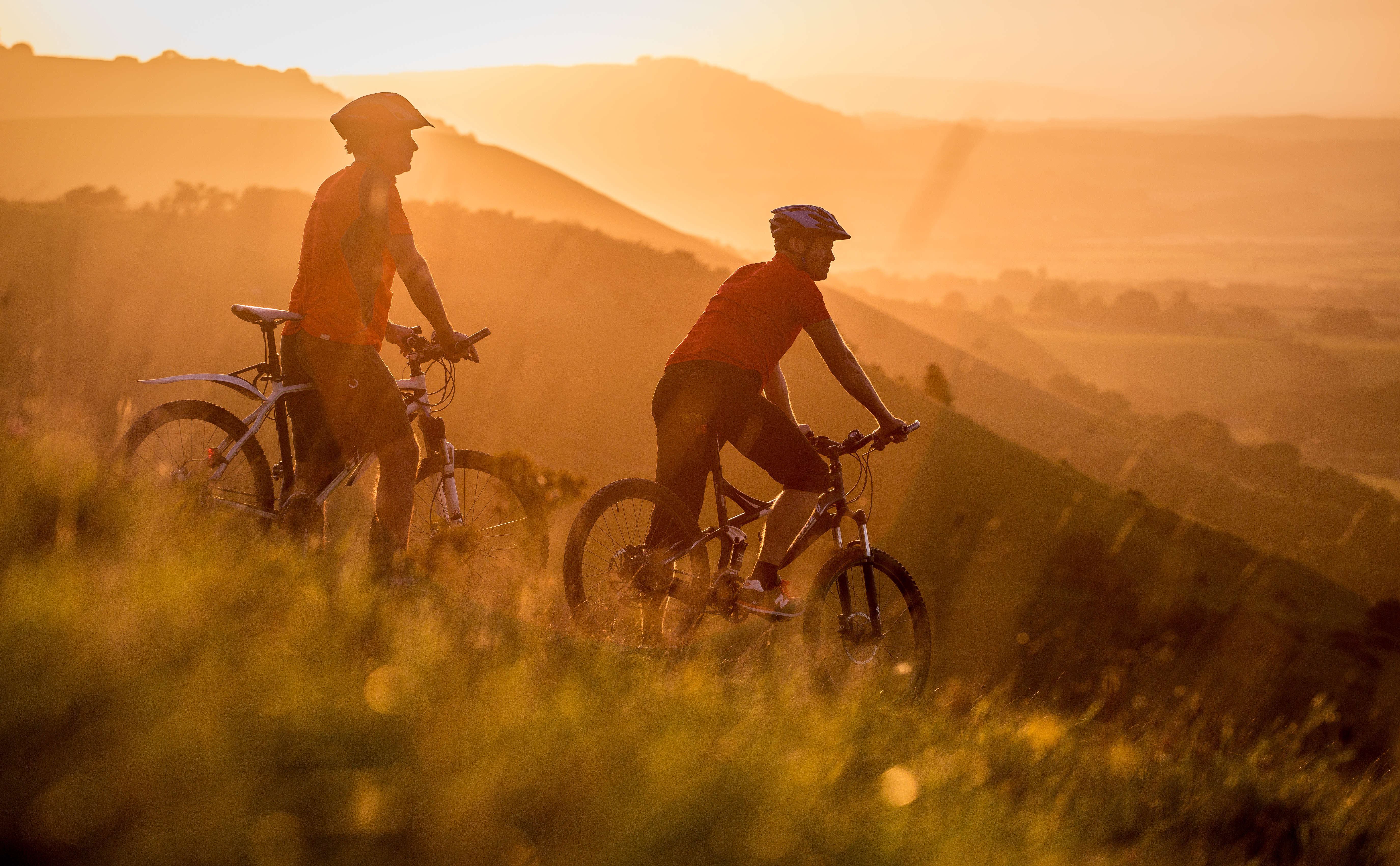 Two men on mountain bikes cycling at Devil's Dyke. Sunrise