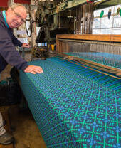 A weaver displaying a working weaving loom at Trefriw Woolen Mills in Snowdonia/Eryri National Park, Wales