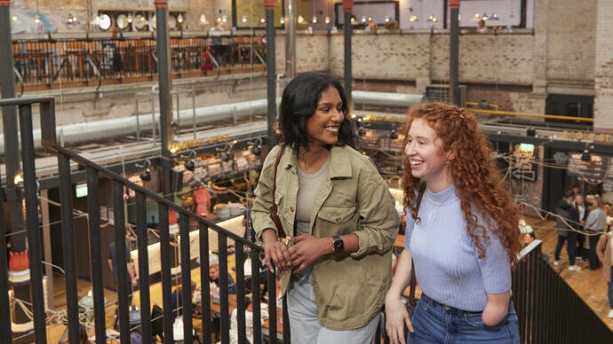 Two women exploring a large open plan food hall.