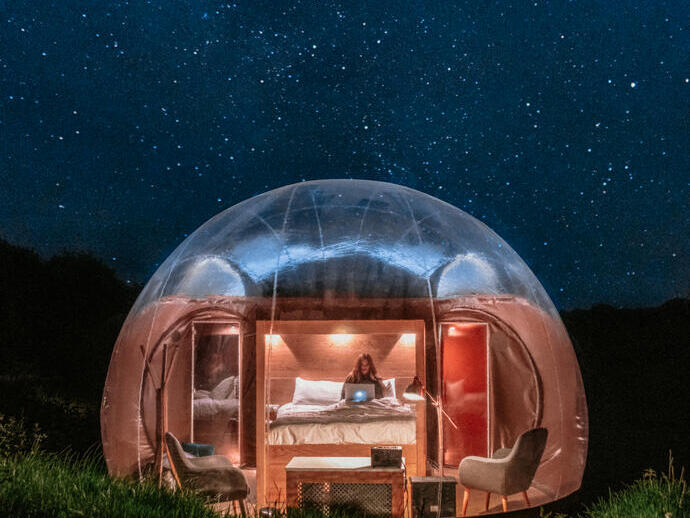 Une femme dans un lit dans une bulle glamping la nuit