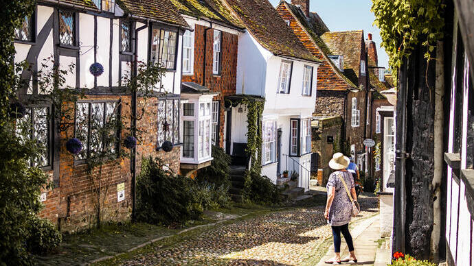 Eine Frau, die eine schmale Dorfstraße hinunterblickt