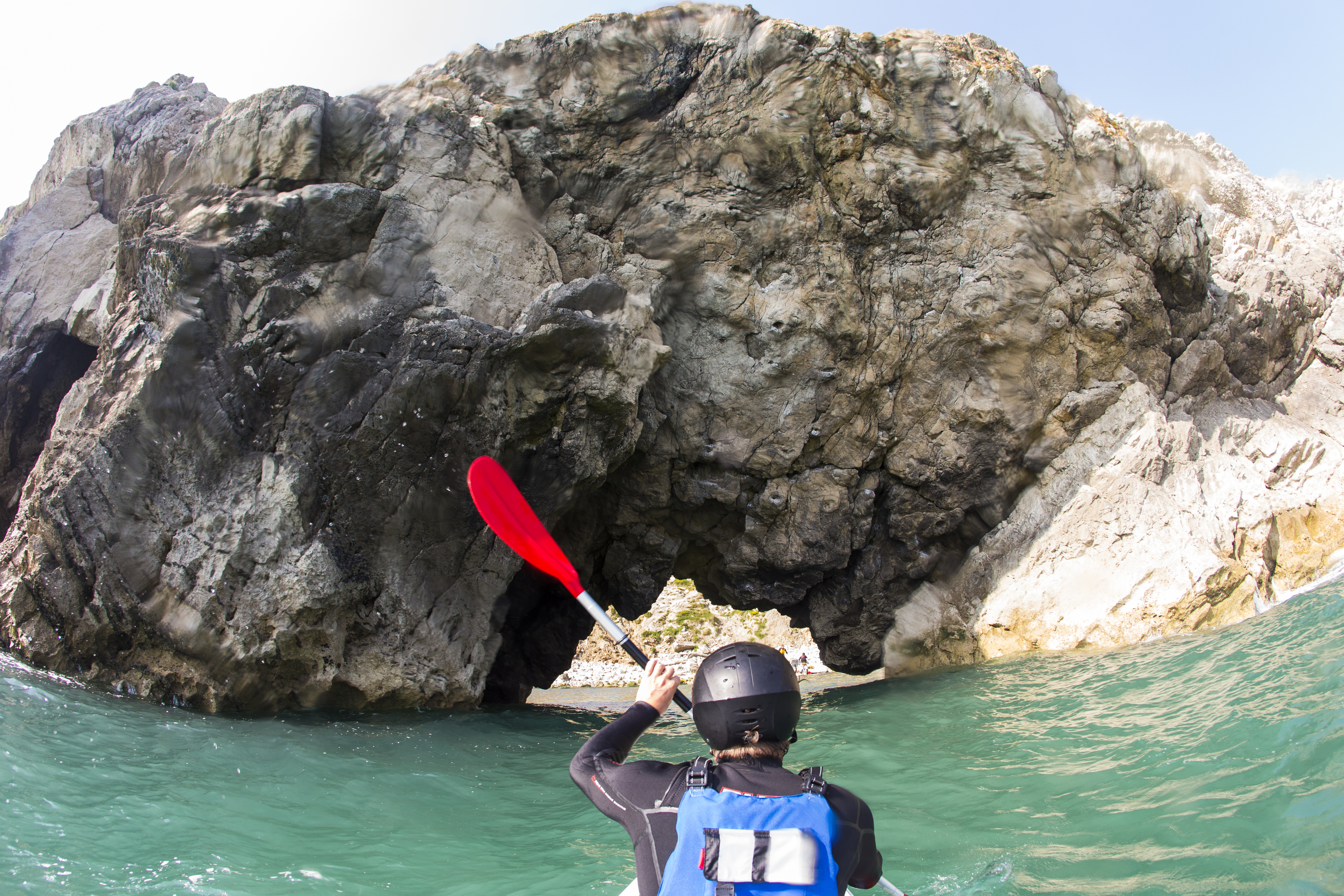 Persona practicando kayak a lo largo de la costa. Acantilado escarpado