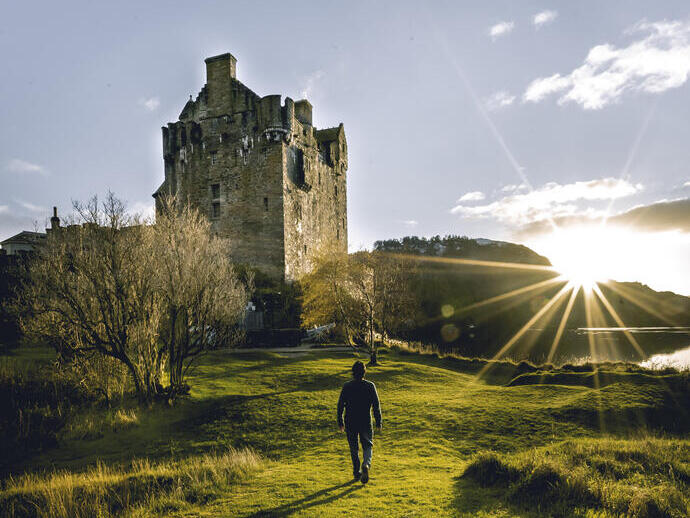 Man walking towards a castle at sunrise