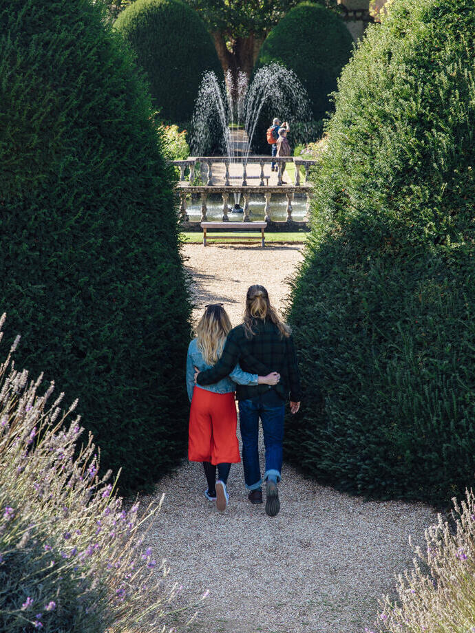 Couple arm in arm walking through formal gardens