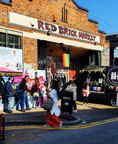 People outside building with sign reading Red Brick Market