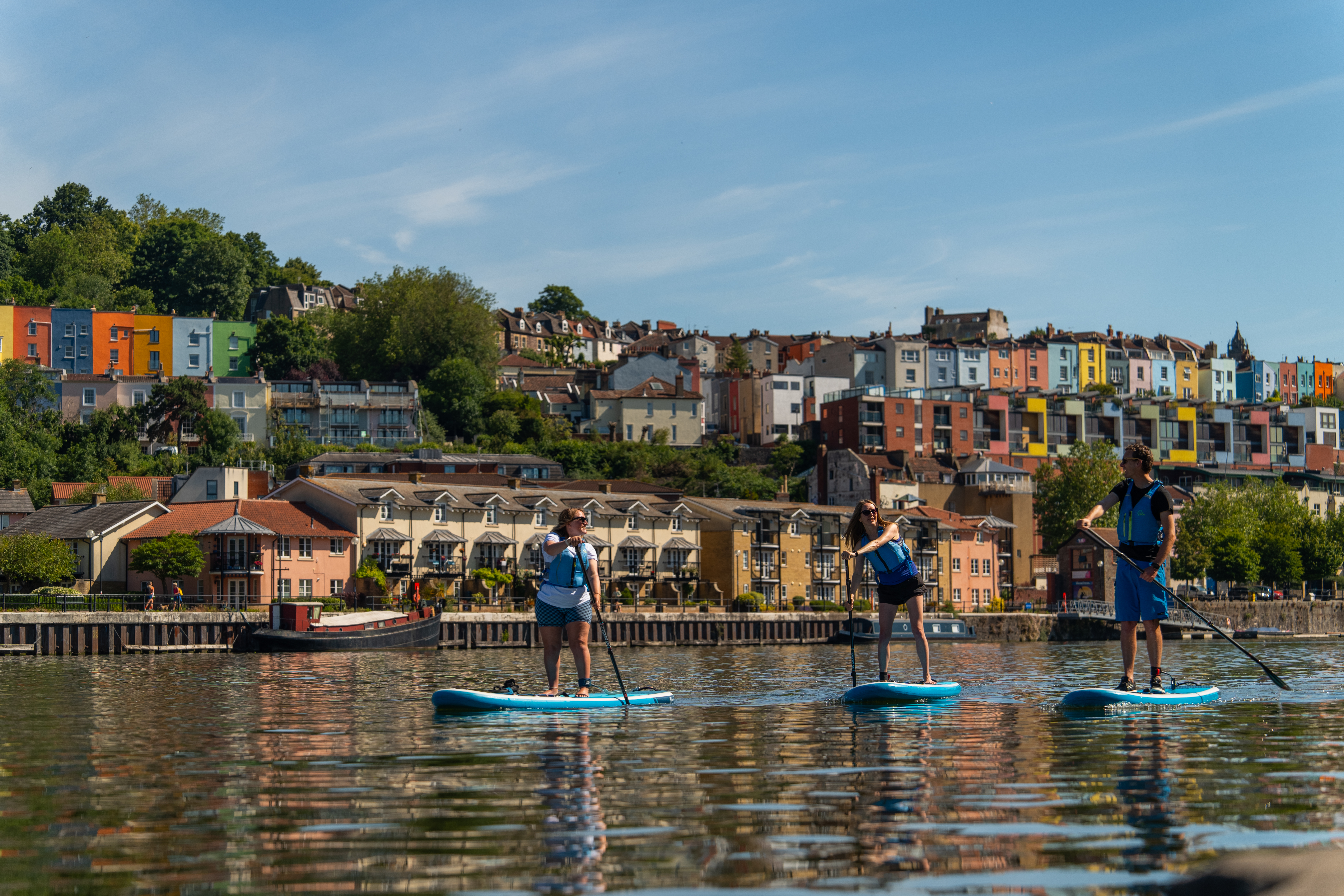 People paddleboarding on the river with the City of Bristol beyond
