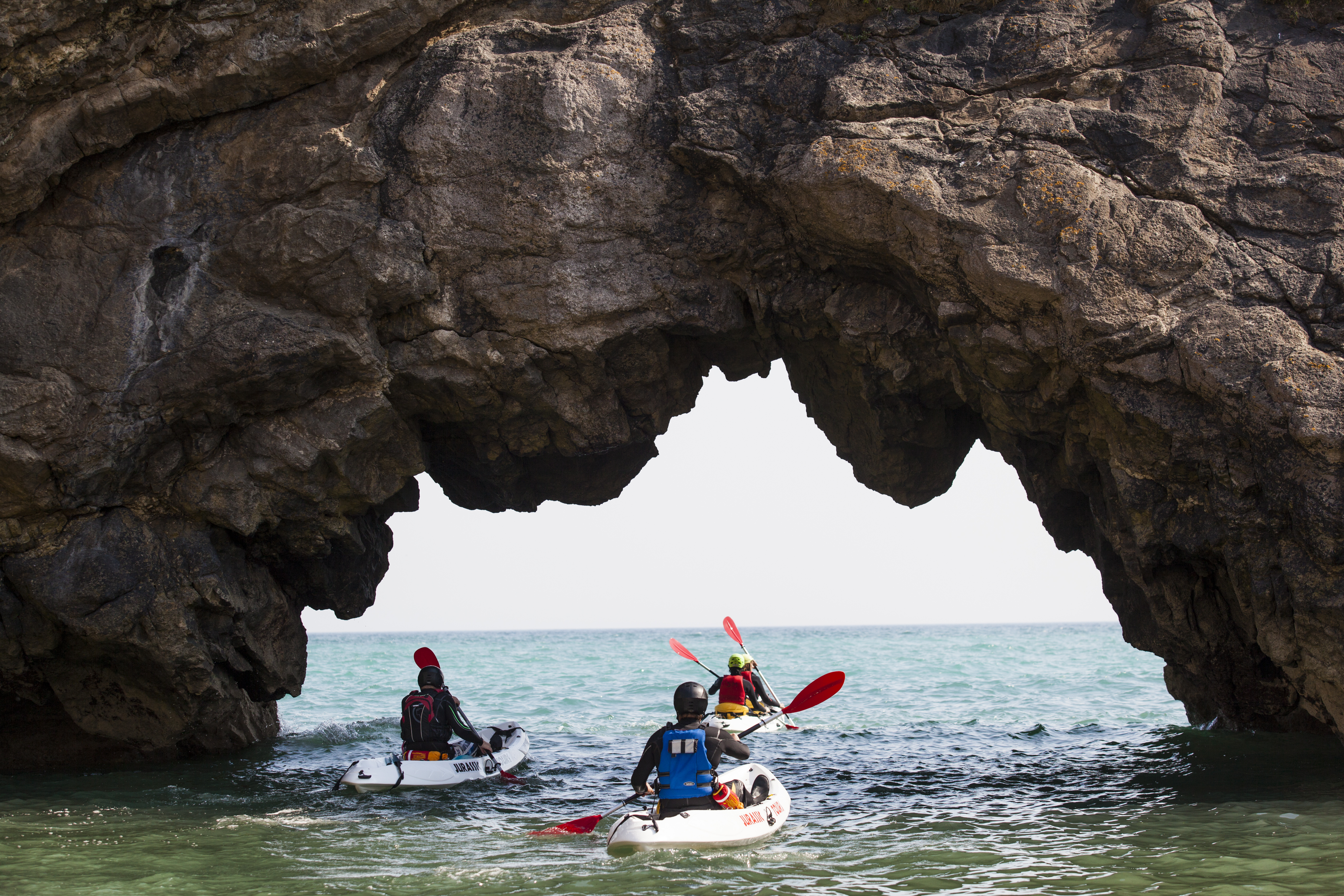 People kayaking under limestone cliffs