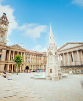 Historical building, with a clock tower, beside a fountain