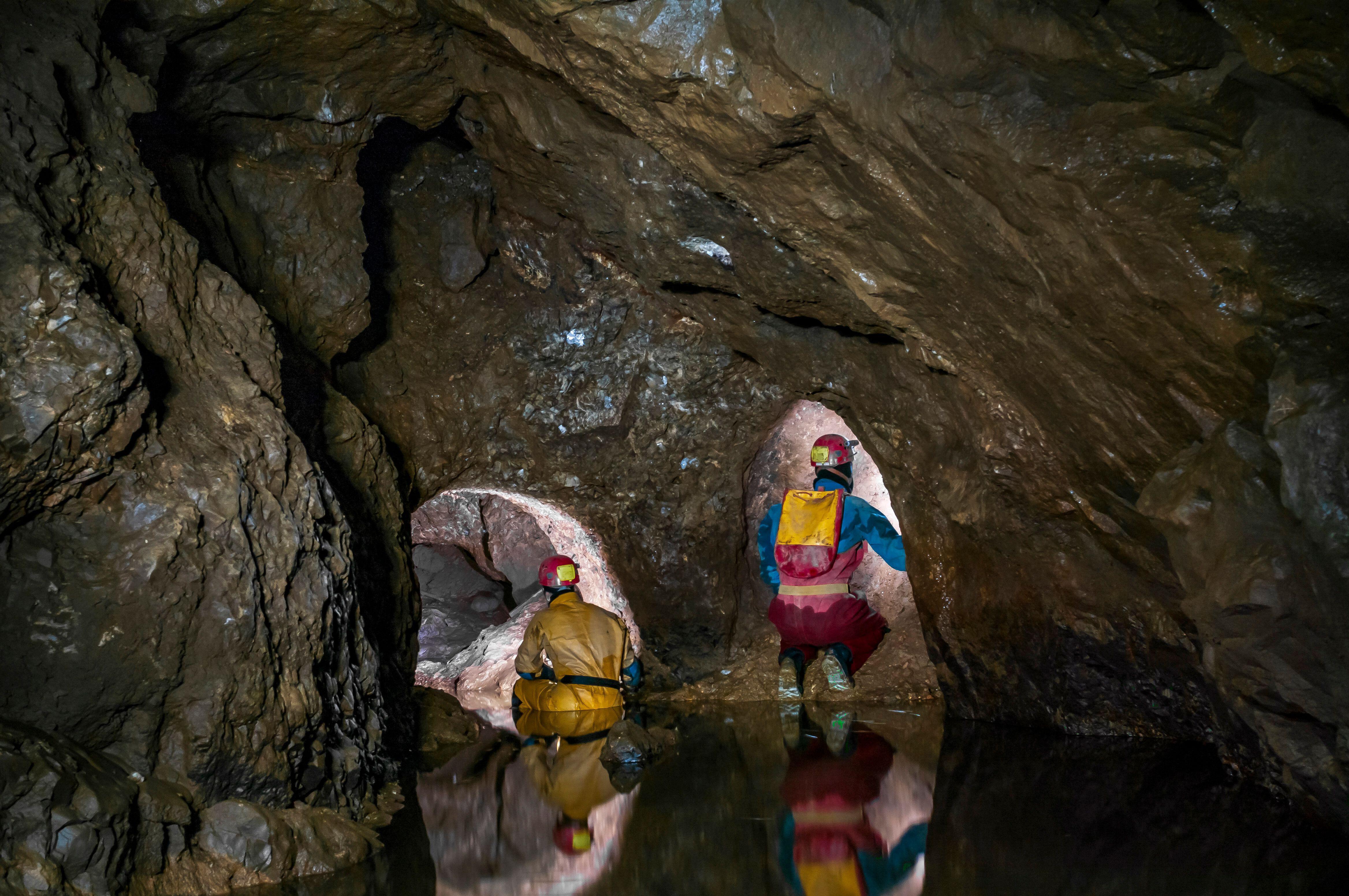 A part-flooded natural cave chamber with two lead miners' tunnels blasted at the far end in Speedwell Cavern in Castleton, Derbyshire.