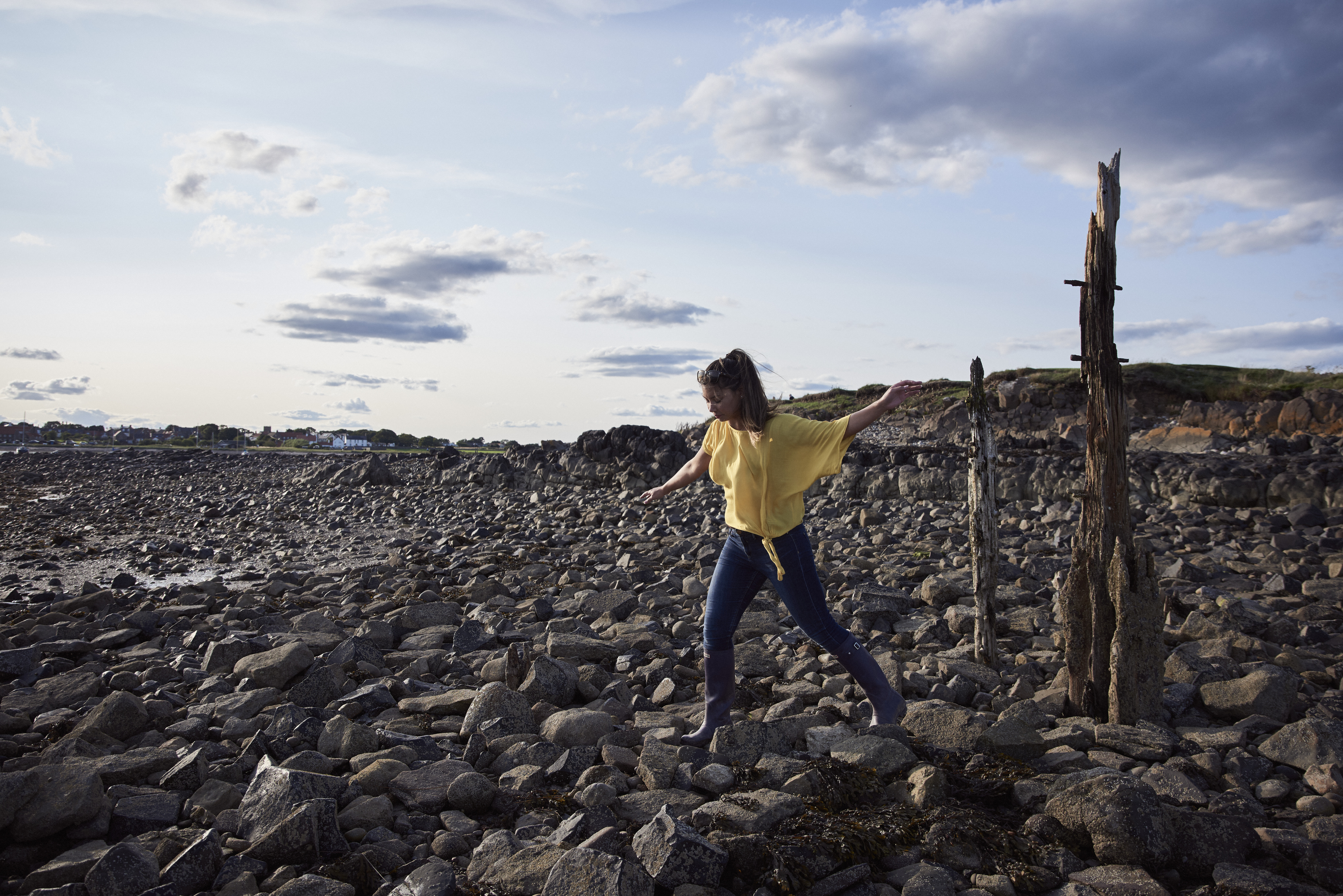 Woman balancing on rocks in between old stakes