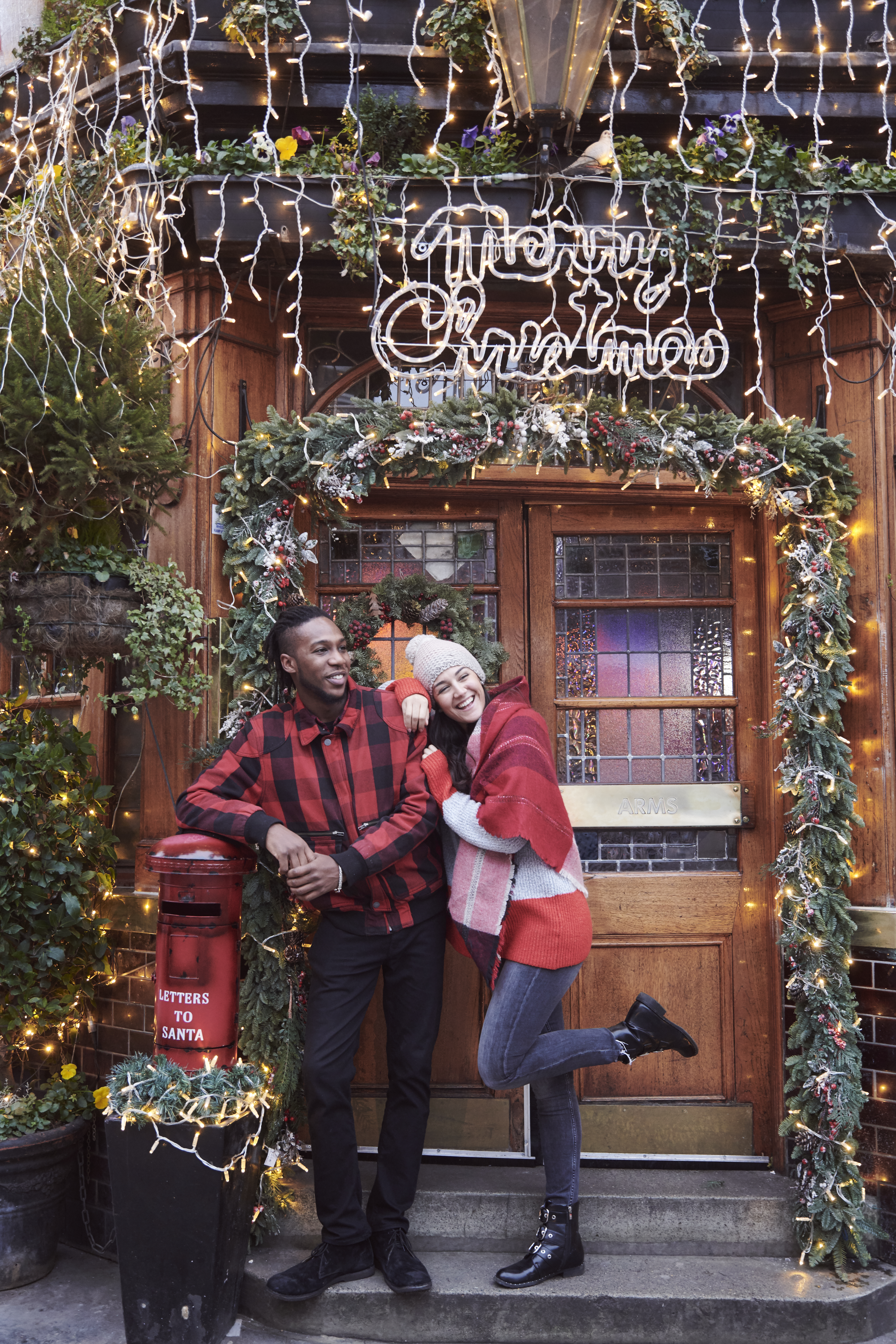Paar vor dem Eingang eines Pubs, der mit Weihnachtsdekoration geschmückt ist