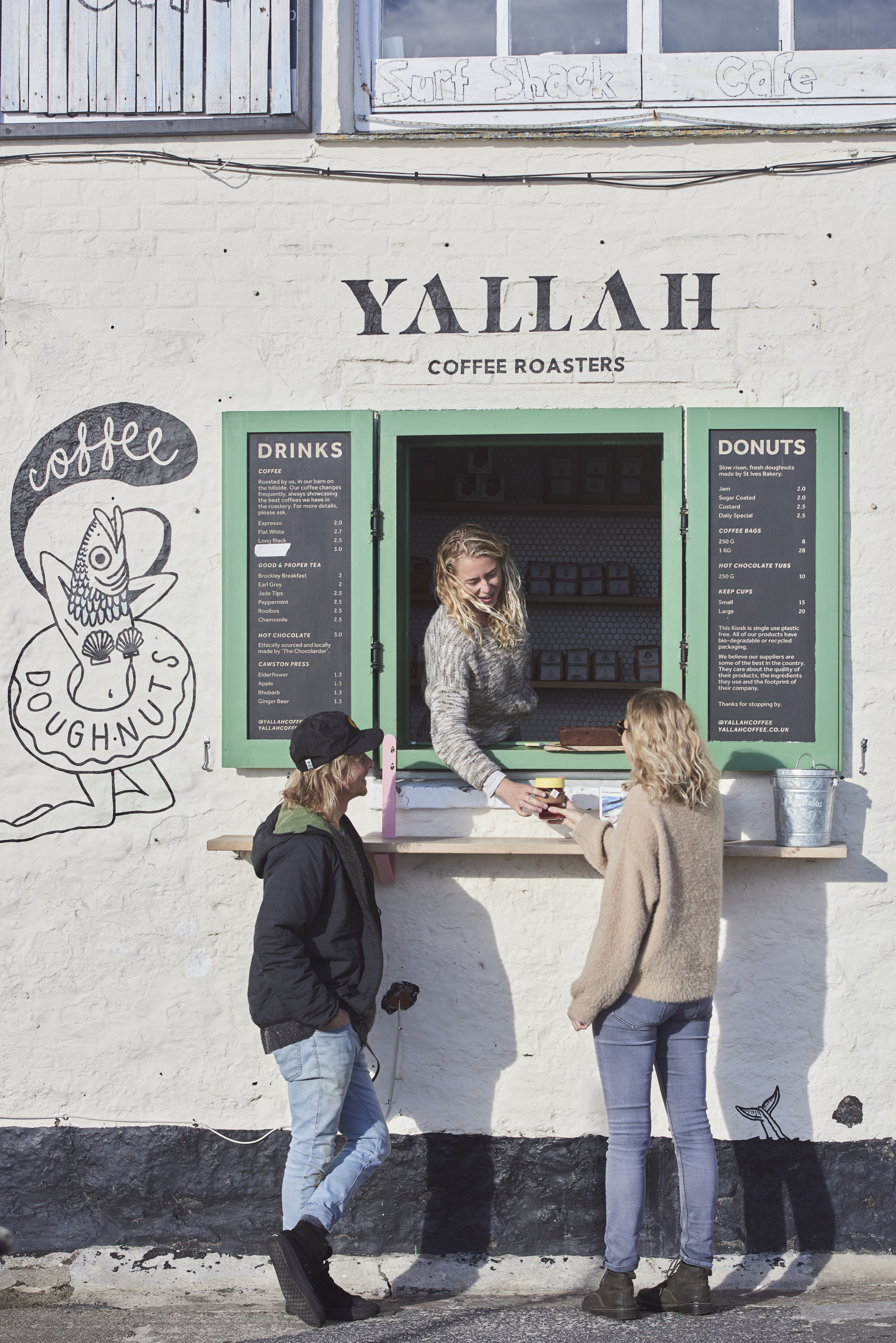 Woman serving coffee through window to two customers